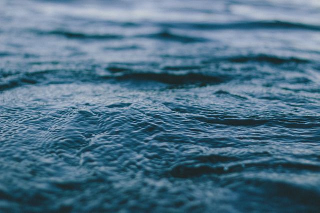 Closeup image showcasing rippling ocean water at dusk. The delicate waves and rich, blue color create a serene and tranquil atmosphere. Ideal for backgrounds, web design, calming themes, environmental topics, and nature-related projects.