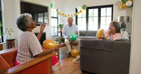 Happy Senior Friends Celebrating Birthday with Balloons in Living Room