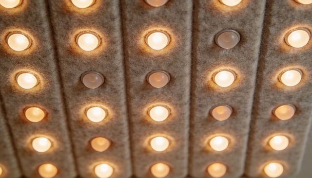 Fabric acoustic ceiling featuring recessed round downlights casting warm halos in grid