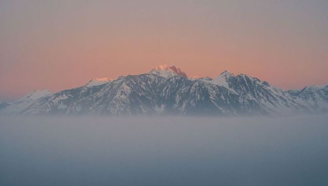 Sunrise Over Misty Snow-Covered Mountain Peaks
