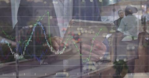 Suited man tapping tablet overlaying financial charts and candlesticks in business lobby