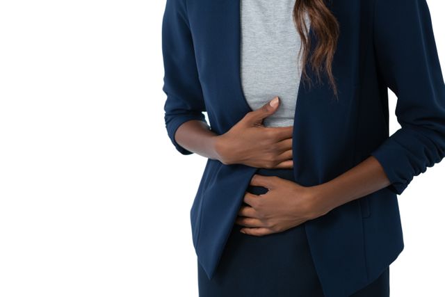 Mid section of woman suffering from stomach ache standing against white background