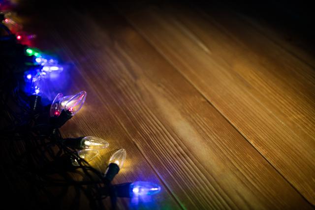 Colorful Christmas lights illuminating on a wooden plank create a festive and warm atmosphere. Ideal for holiday marketing, seasonal greetings, festive decoration ideas, or as a background image for Christmas events and celebrations.