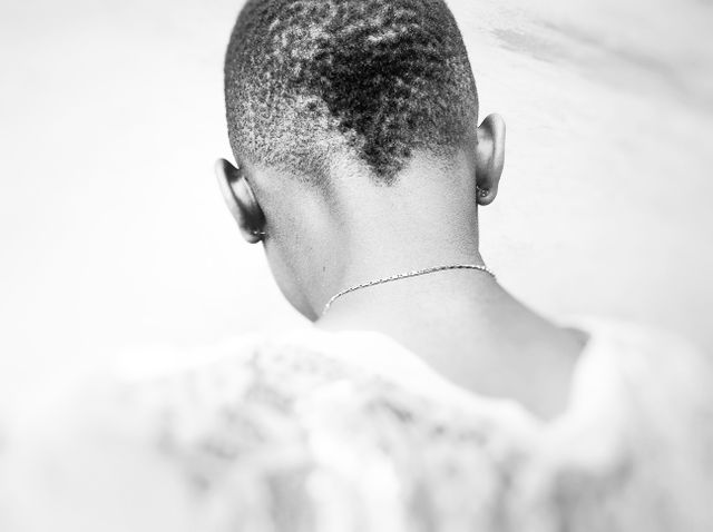 This image captures the rear view of a person with short, styled hair and earrings. The focus is on the unique hair pattern and the subtle details of the jewelry. It highlights a sense of individuality and simplicity. This image is great for use in design projects, fashion articles, or blogs focusing on personal style and identity.