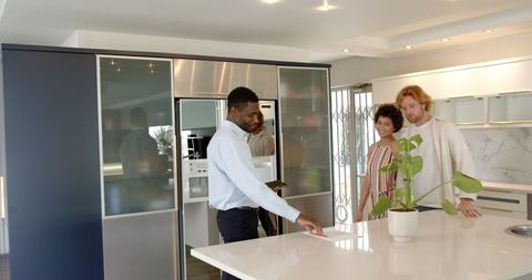 Couple with Real Estate Agent Concluding House Tour in Modern Kitchen