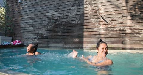 Mother and daughter enjoy splashing in backyard pool