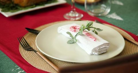 Festive holiday table setting with candy cane and frosted sprig