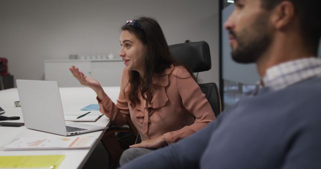 Caucasian businesswoman sitting with laptop talking to male colleague at casual office meeting. independent creative business in a modern office.