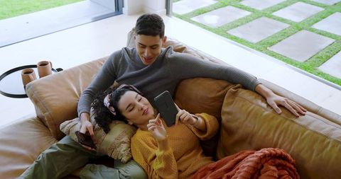 Relaxed Couple Using Smartphones on Cozy Leather Sofa