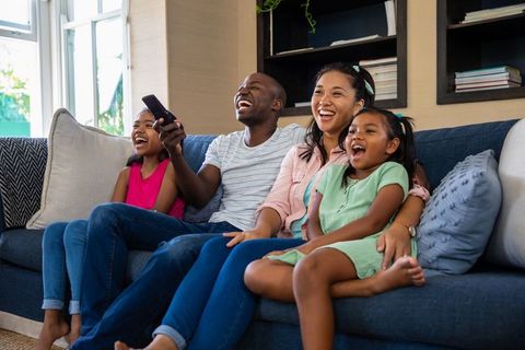 Happy Family Watching Television Together on Cozy Sofa