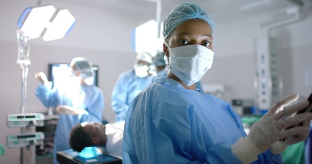 Diverse surgeons with face masks during surgery on african american male patient. Medicine, healthcare, surgery and hospital, unaltered.
