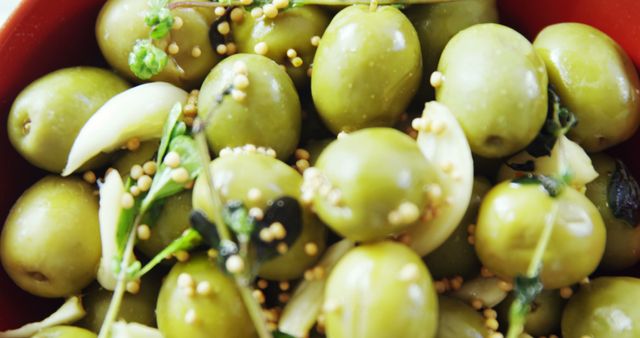 A close-up view of marinated green olives garnished with herbs and spices, showcasing a Mediterranean appetizer. Vibrant colors and textures invite a sensory experience of fresh and savory flavors.