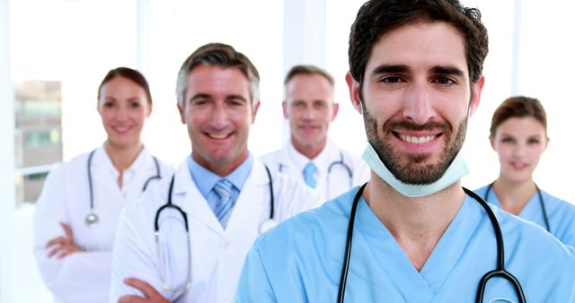Smiling medical professionals posing together in bright hospital. Perfect for promoting healthcare services, medical team unity, and professional healthcare environments. Ideal for websites, brochures, and advertisements related to medical and clinical services.