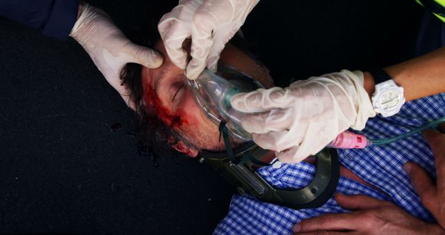 Paramedics providing life-saving assistance to a man injured in an accident. This scene illustrates a critical medical emergency, with focus on the paramedics' swift and professional care, including administering an oxygen mask. Suitable for use in discussions about emergency response, first aid, healthcare services, rescue operations, and trauma care awareness.