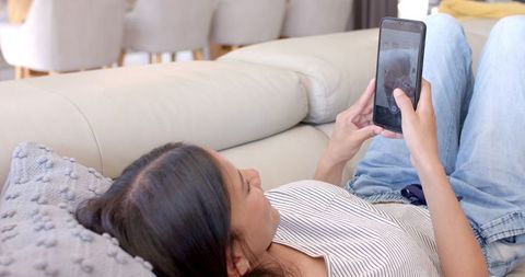 Teenage girl relaxing on couch using smartphone at home