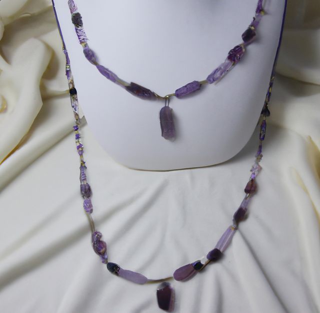 In this image, we see a beautifully crafted amethyst beaded necklace set elegantly arranged on a white display bust against a soft, cream fabric background. Perfect for showcasing handmade jewelry collections, fashion accessory promotions, gemstone ads, and artisan craft catalogs.