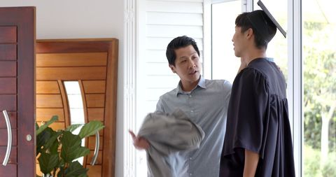 Father Supporting Graduate Son at Home on Graduation Day