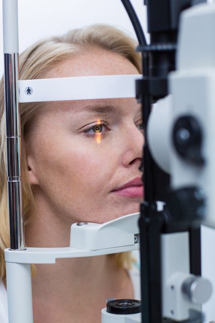 Close-up of a patient undergoing an eye examination using a slit lamp in an ophthalmology clinic. Ideal for use in medical articles, healthcare brochures, eye care advertisements, and educational materials about vision health and diagnostic procedures.
