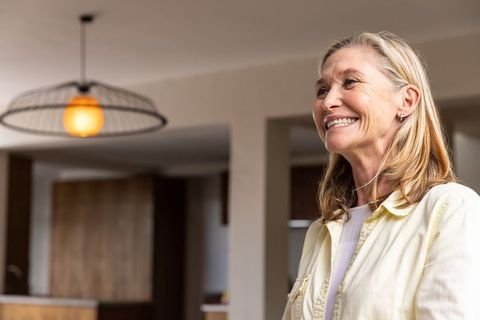 Senior woman smiling in modern kitchen with warm lighting
