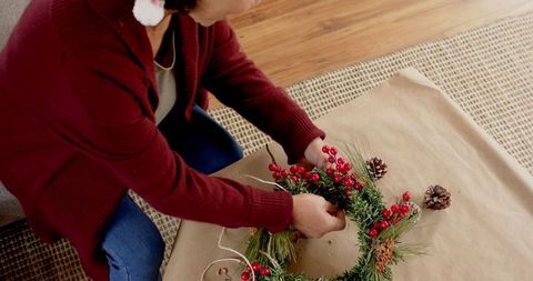 Senior woman arranging holiday wreath at home
