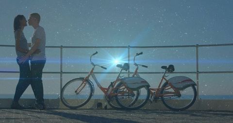Romantic Couple Embracing Near Rental Bikes at Dusk