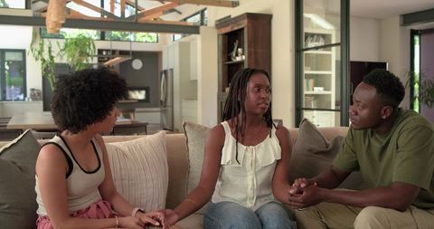 African American friends comforting one another on sofa offering support and empathy