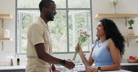 Couple sharing flowers in bright modern kitchen showing warm everyday romance