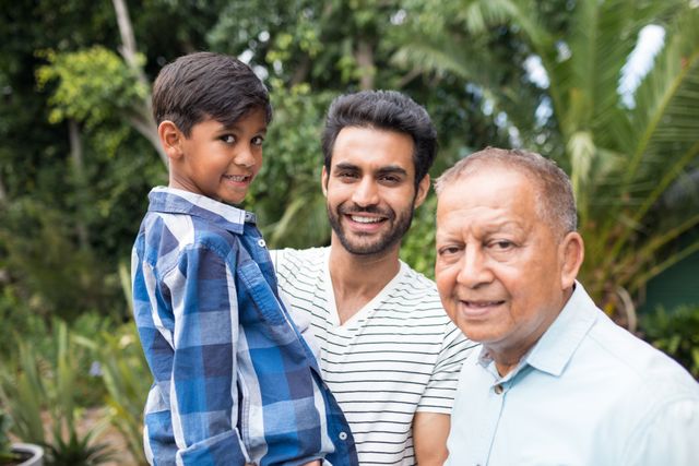 Portrait of father carrying son while standing by senior man at home