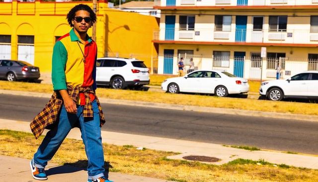 Colorblock street style man walking with sunglasses and plaid shirt tied around waist