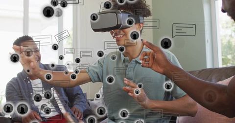 Young man interacting with virtual social chat using vr headset on sofa at home