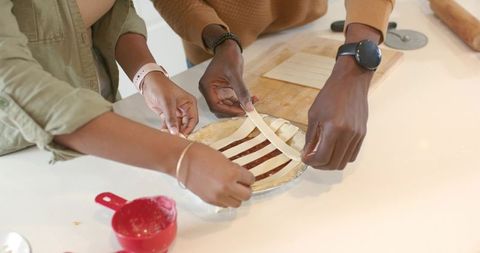 African american couple weaving lattice crust while assembling homemade fruit pie together