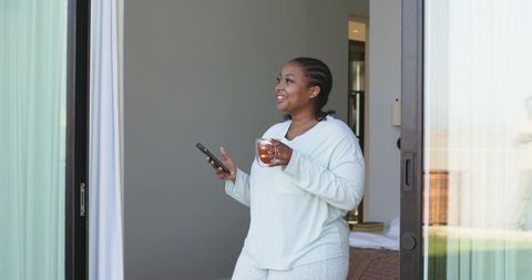 African american woman enjoying morning tea on patio in cozy loungewear
