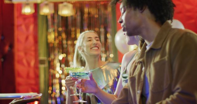 Image of diverse group of happy male and female friends drinking cocktails standing at a bar. Friendship, going out, drinking and socialising concept.