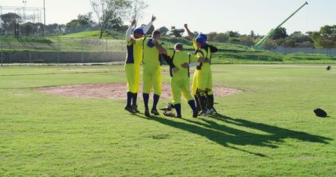 Male Baseball Team Huddling and Celebrating Victory on Pitcher Mound in Yellow Uniforms