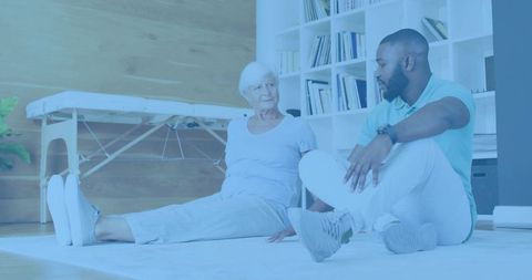 Therapist guiding senior woman performing seated stretch during rehabilitation session