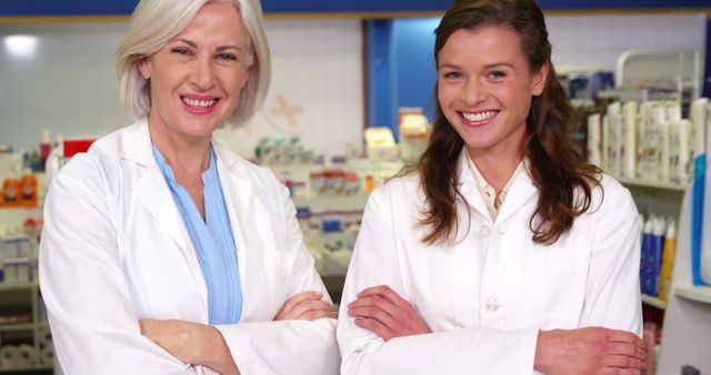 Portrait of smiling pharmacists standing with arms crossed in pharmacy