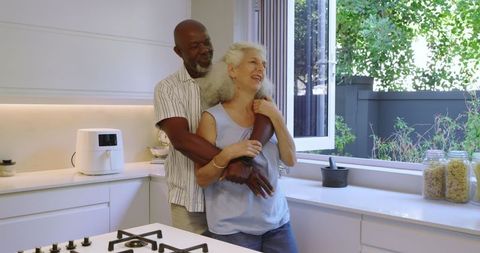 Affectionate senior couple embracing in modern home kitchen
