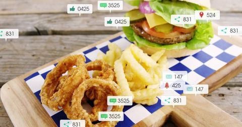 Rustic burger with onion rings and crinkle fries on wooden board with social overlays