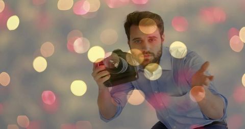 Crouching photographer holding dslr camera with bokeh background