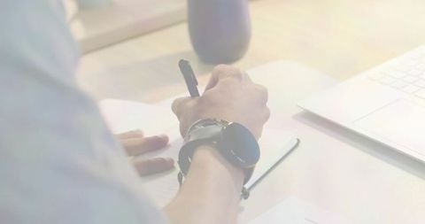 Writing on Spiral Notebook with Smartwatch and Laptop at Minimalist Home Office Desk