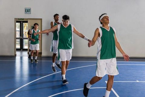 Teenage basketball team stretching on indoor court