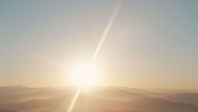 Serene Sunrise Over Misty Mountain Ridges with Soft Rays