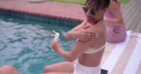 Applying sunscreen at poolside during sunny backyard gathering with friends