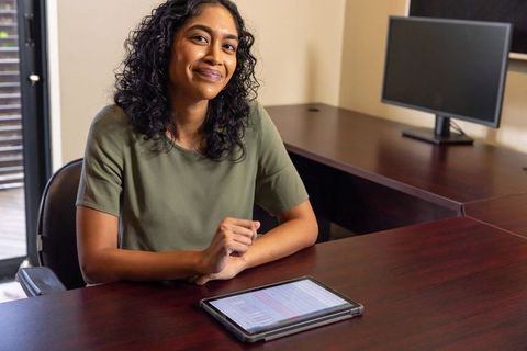 Confident businesswoman using tablet at office desk for work productivity