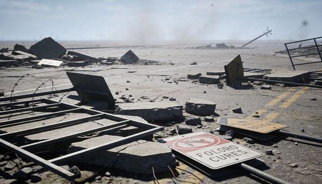 Desolate highway wreckage with fallen barricades, cracked concrete and broken road signs