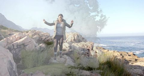 Woman hiking adventure on windy rocky coast for outdoor exploration