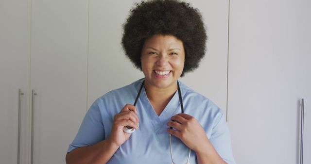 Nurse smiling and holding stethoscope while standing in a hospital ward. Ideal for healthcare advertisements, medical brochures, and promotional materials showcasing hospital staff and patient care.