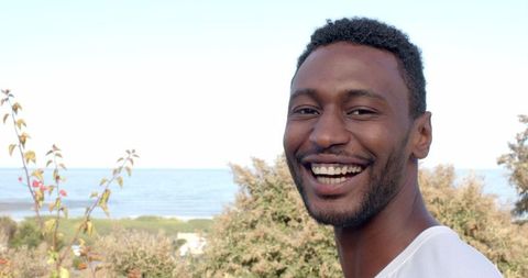 Man smiling outdoors with ocean background