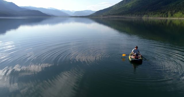 Man Paddling Canoe on Serene Lake Surrounded by Mountains - Download Free Stock Images Pikwizard.com