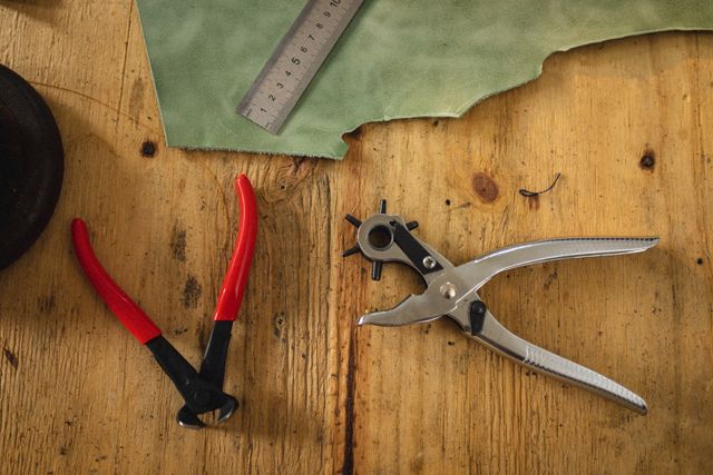 Directly above shot of punch plier and equipment with ruler on leather at workbench. unaltered, small business, still life, handcraft, equipment, leather craft and workshop.